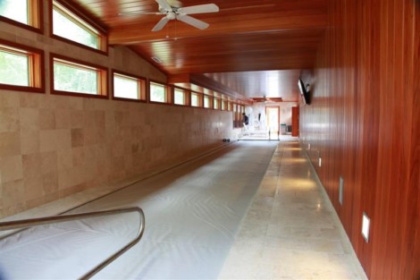 Indoor pool with automatic cover, wooden walls, and natural lighting, perfect for year-round swimming. Indoor pool with wooden walls and automatic cover, Long Island.