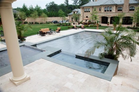 Elegant inground pool with automatic cover, surrounded by outdoor furniture and lush landscaping in Long Island. Luxury inground pool with automatic cover and outdoor furnishings in Long Island.