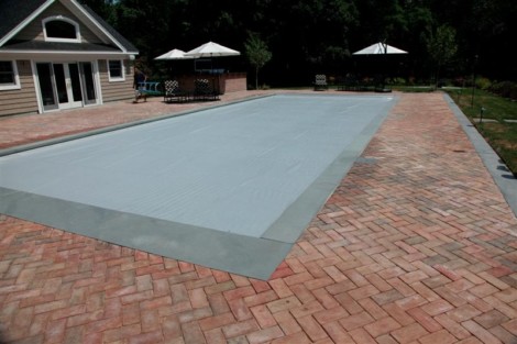 Beautiful inground pool with automatic cover, surrounded by a brick patio and outdoor seating area in Long Island. Inground pool with automatic cover and brick patio in Long Island.