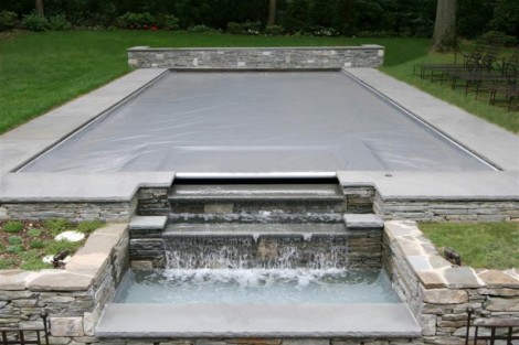 Luxury inground pool with automatic cover, waterfall, and outdoor furnishings in Long Island. Long Island inground pool with automatic cover and waterfall feature.