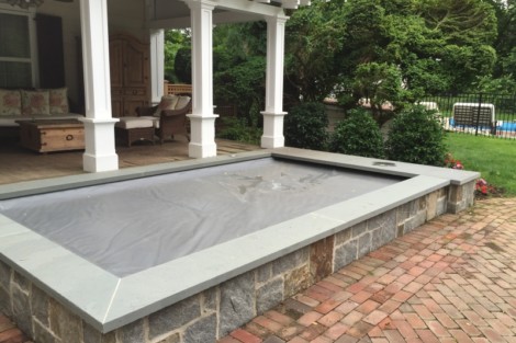 Beautiful inground pool with a sleek automatic cover, perfect for outdoor relaxation and entertainment. Long Island inground pool with automatic cover and stone border.