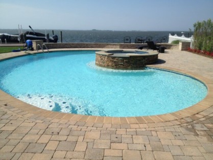 Luxury inground pool with hot tub and outdoor furnishings overlooking Long Island waterfront. Beautiful inground pool with hot tub and waterfront view in Long Island.