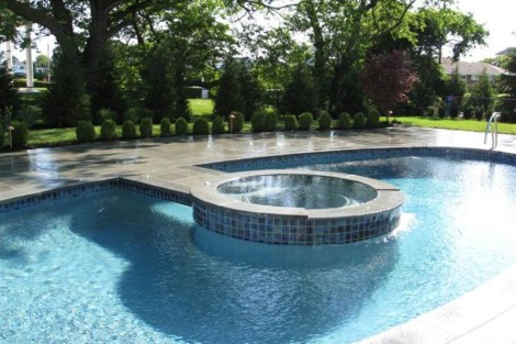 Luxury inground pool with attached hot tub and landscaped backyard in Long Island. Beautiful inground pool with hot tub and lush greenery in Long Island.