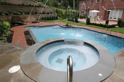 Beautiful backyard with inground pool, hot tub, and outdoor furnishings on Long Island. Luxury inground pool with hot tub and water features in backyard.