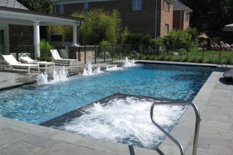 Luxury inground pool with hot tub, outdoor furniture, and lush landscaping in Long Island backyard. Beautiful inground pool with hot tub and outdoor lounging area in Long Island.