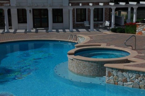 Beautiful inground pool with attached hot tub and outdoor seating area in Long Island, NY. Inground pool with hot tub and outdoor furnishings in Long Island.