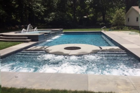 Elegant inground pool with integrated spa and water features, perfect for outdoor relaxation and entertainment. Beautiful inground pool with spa and water features in a backyard setting.