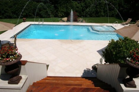 Beautiful inground pool with water fountains, surrounded by outdoor furniture and lush greenery in Long Island. Inground pool with water fountains and outdoor furnishings in Long Island.