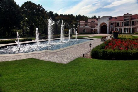 Elegant inground pool with multiple fountains at a luxurious estate in Long Island, surrounded by lush landscaping. Luxury inground pool with fountains at a mansion in Long Island.
