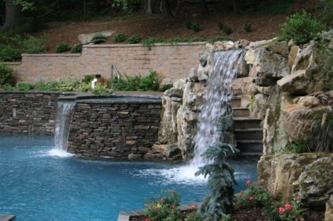 Beautiful inground pool with waterfall and natural rock landscaping in Long Island backyard. Inground pool with waterfall and natural rock features in Long Island.