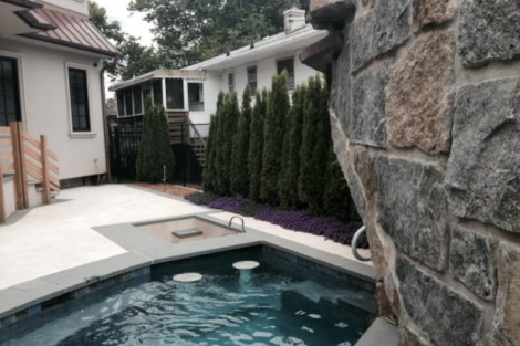 Beautiful inground pool with water features, surrounded by outdoor furnishings and lush landscaping in Long Island. Inground pool with water features and outdoor furnishings in Long Island.