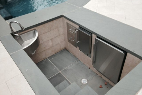Modern outdoor bar with sink, mini fridge, and storage, perfect for outdoor gatherings and water features. Outdoor bar with sink, mini fridge, and storage for outdoor entertaining.