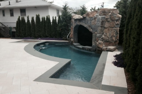 Beautiful inground pool with waterfall feature, surrounded by outdoor furnishings and lush landscaping in Long Island. Inground pool with waterfall feature and outdoor furnishings in Long Island.