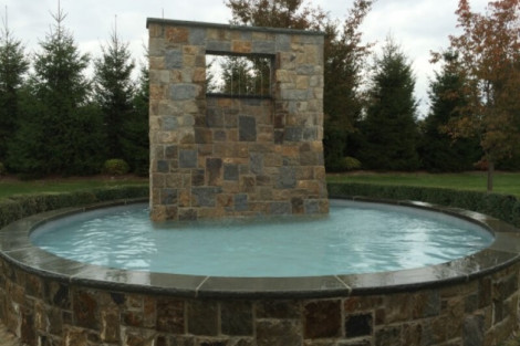 Elegant stone pool with water feature, perfect for outdoor relaxation and entertainment in Long Island. Stone pool with water feature and outdoor landscape in Long Island.