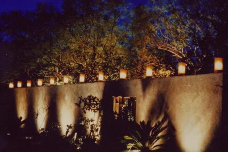 Elegant outdoor lighting setup with lanterns and wall lights illuminating a garden at night. Nighttime garden lighting with lanterns and wall lights for outdoor ambiance.