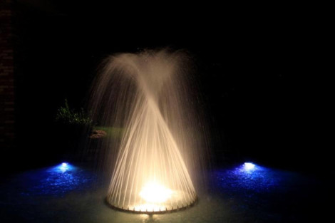 A beautifully lit fountain at night with water jets and colorful lighting effects. Nighttime fountain with colorful lighting and water jets.