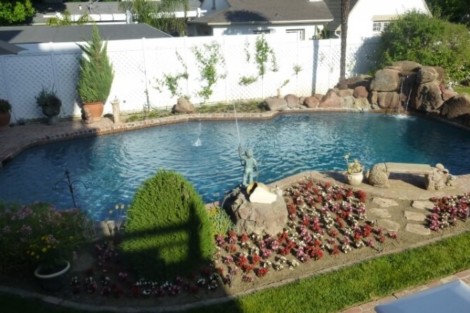 Elegant inground pool with surrounding landscaping and outdoor furniture in Long Island backyard. Beautiful backyard with custom inground pool and outdoor furnishings in Long Island.