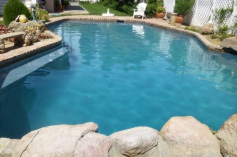 Elegant inground pool with natural stone border, perfect for outdoor relaxation and entertaining in Long Island. Beautiful inground pool with natural stone border and outdoor furnishings.