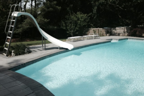Beautiful inground pool with slide and outdoor furniture in a lush backyard setting in Long Island. Inground pool with slide and outdoor furnishings in Long Island.