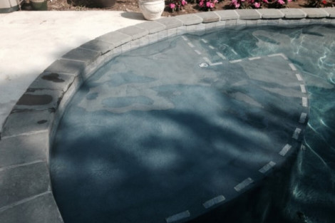 Beautiful inground pool with stone border and lush flowers in Long Island backyard. Inground pool with stone border and surrounding flowers in Long Island.