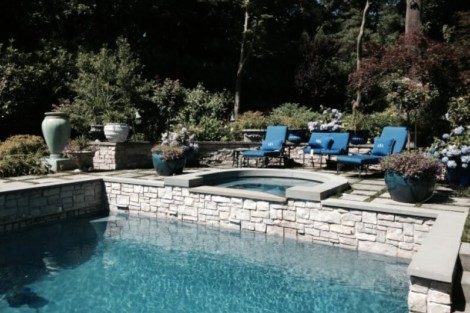 Elegant outdoor pool area with lounge chairs and vibrant plants, perfect for relaxing and entertaining. Beautiful inground pool with lounge chairs and lush landscaping in Long Island.