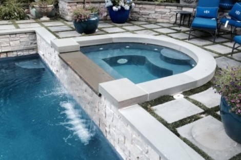 Elegant backyard with inground pool, hot tub, and outdoor seating area by All Island Group. Luxury inground pool and hot tub with outdoor furnishings on patio.
