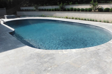 Custom inground pool with stone surround and lush landscaping in Long Island, perfect for outdoor living and relaxation. Beautiful inground pool with stone deck and landscaped yard in Long Island.