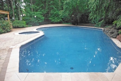 Elegant inground pool with lush greenery and outdoor furnishings in Long Island, perfect for outdoor living and relaxation. Beautiful inground pool with surrounding outdoor furnishings in Long Island.