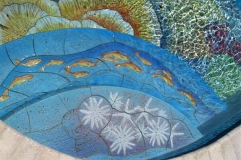 Close-up of a custom tile pool featuring marine life and coral designs for a luxurious outdoor space. Colorful custom tile pool with marine life and coral patterns.