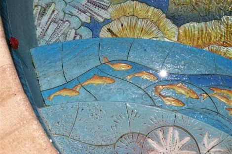 Close-up of a custom mosaic tile pool featuring fish and aquatic themes, perfect for outdoor luxury settings. Colorful mosaic tile pool with fish and aquatic motifs.