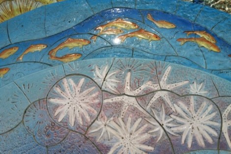 Close-up of a vibrant custom tile mosaic featuring sea life and starfish, perfect for outdoor pool areas. Colorful custom tile mosaic with sea creatures and starfish.