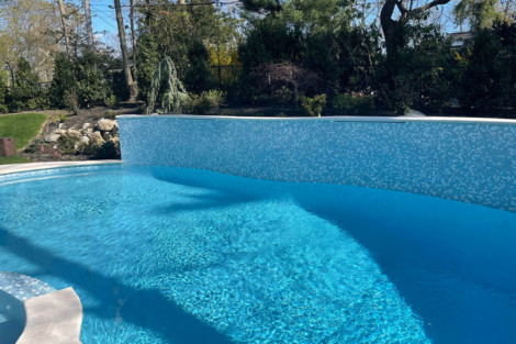 Custom inground pool with mosaic tile wall, perfect for outdoor relaxation and entertainment. Beautiful inground pool with mosaic tile wall and outdoor scenery.