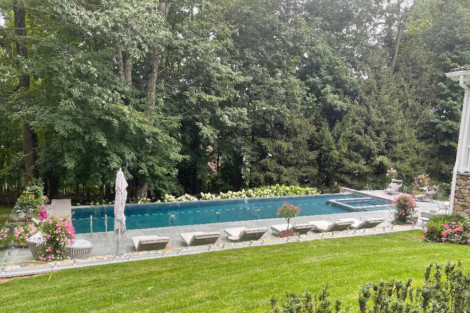 Beautiful inground pool with outdoor furnishings and lush greenery in Long Island, perfect for outdoor relaxation. Inground pool with surrounding outdoor furnishings and lush greenery.
