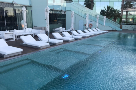 Elegant poolside setup with white lounge chairs and umbrellas for relaxation and outdoor enjoyment. Modern outdoor pool with white lounge chairs and umbrellas.