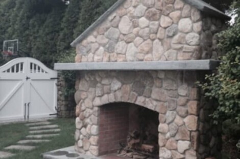 Elegant outdoor stone fireplace with chimney, perfect for outdoor gatherings and patio ambiance. Outdoor stone fireplace with chimney and hearth for patio.
